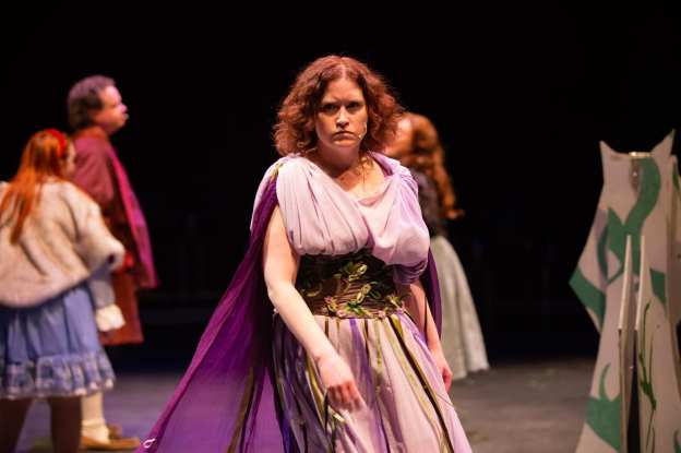 Female actor in draped purple costume playing The Witch